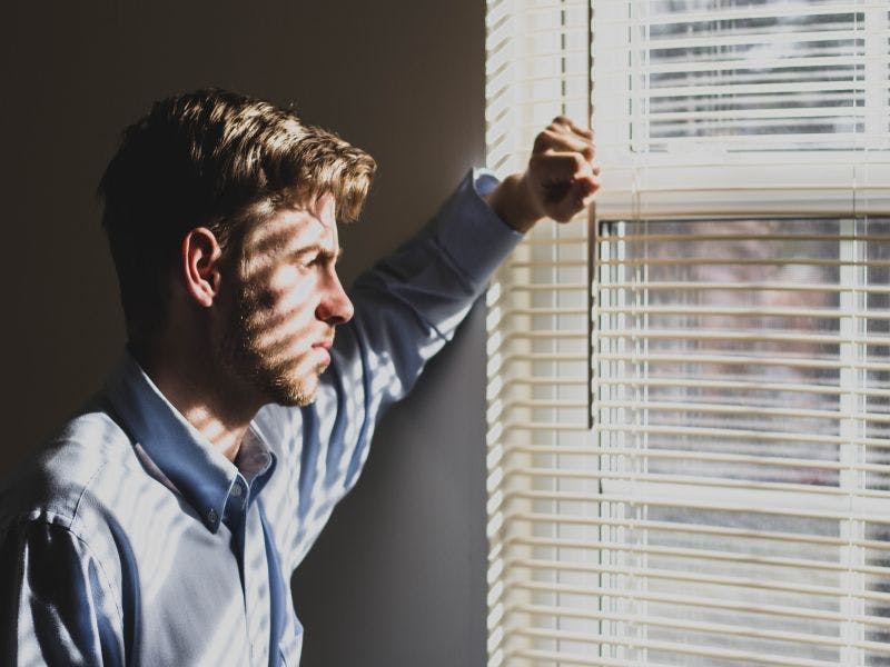 concerned young man looking out of window