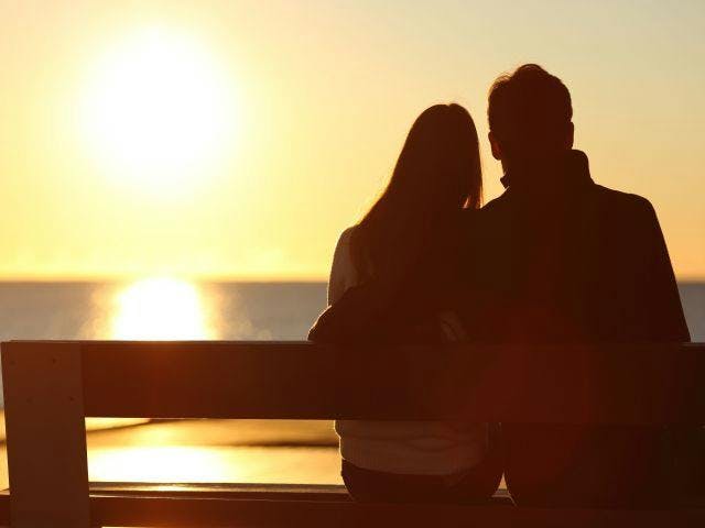 Couple in silhouette sitting on bench