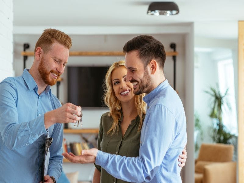 Photo of young couple getting keys to property