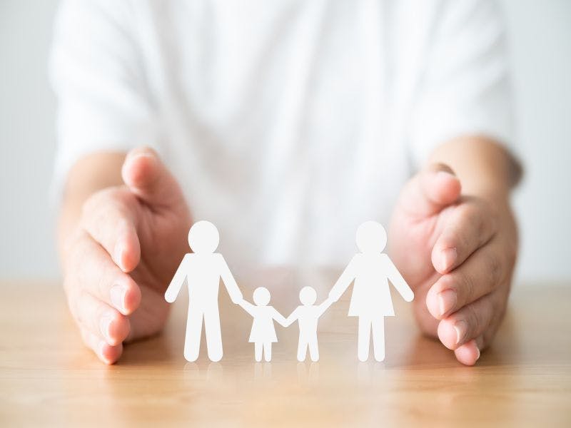 Image of hands protecting family cut-out figures